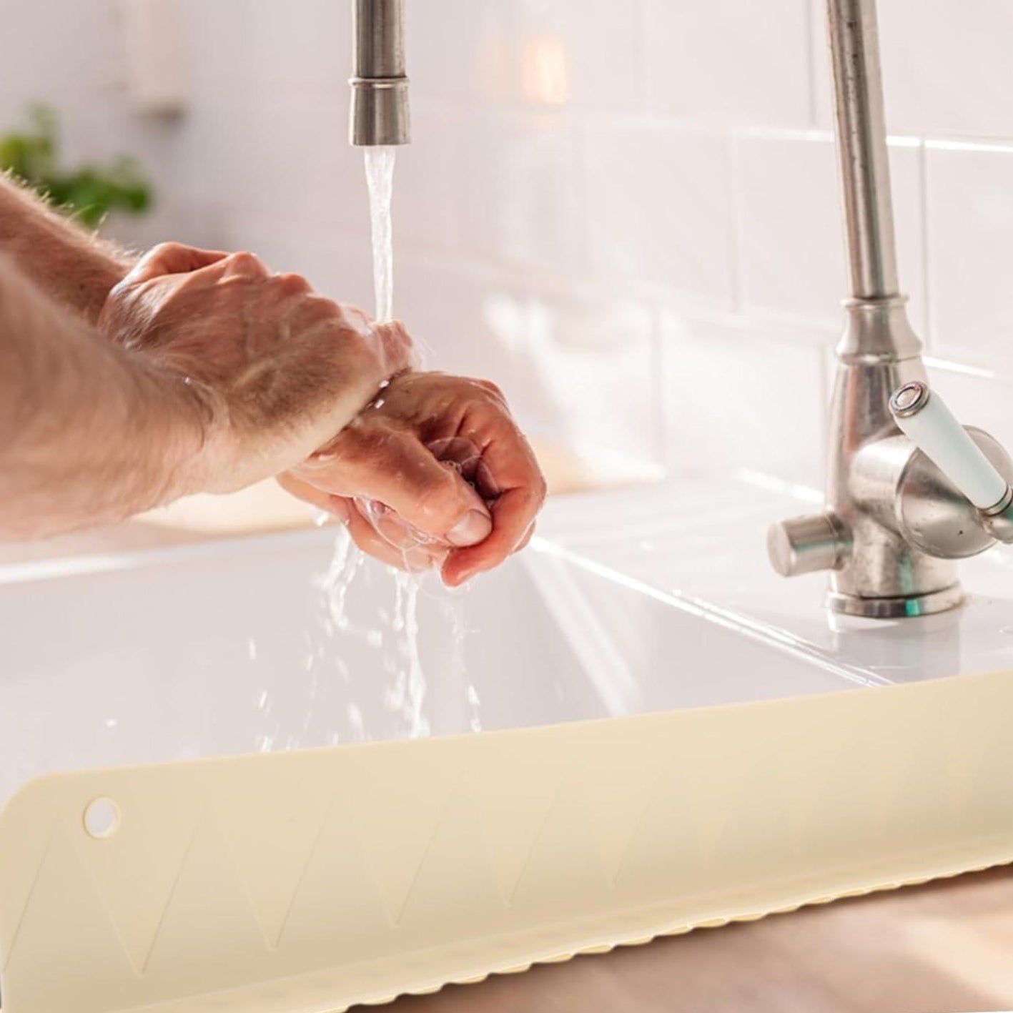 Person washing hands under a faucet with a kitchen sink in the background
